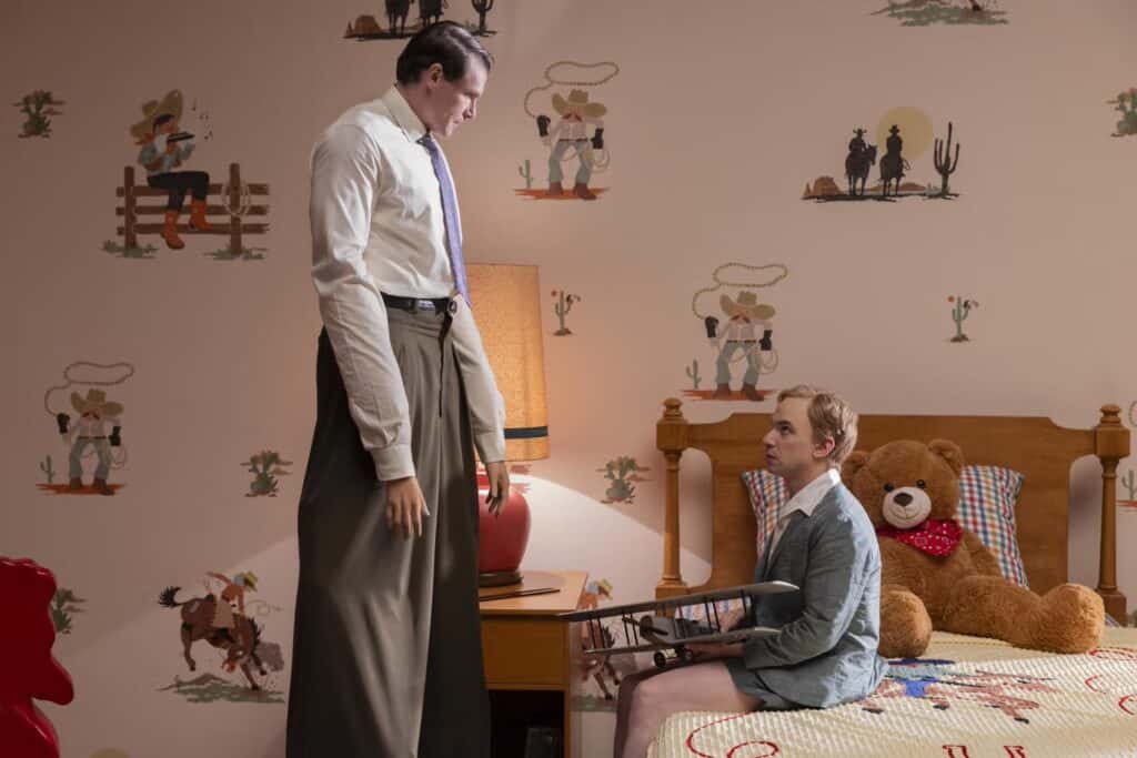 Nathan Fielder looks up at an actor on stilts as he portrays a young Sully Sullenberger.
