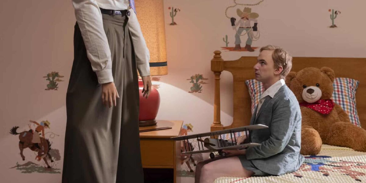 Nathan Fielder looks up at an actor on stilts as he portrays a young Sully Sullenberger.
